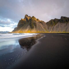 Dramatic black sand beach meets dramatic mountain range at golden hour