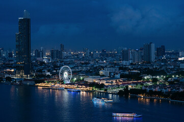 Obraz premium Night view of Asiatique The Riverfront in Bangkok with illuminated ferris wheel, riverside market, and boats on Chao Phraya River. BKK, Thailand. 7 Sep 2024