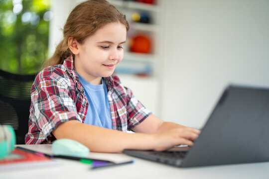 Kid using laptop for online studying at home. Child sitting at desk with laptop on virtual school lesson. Child learning with laptop. Young student . Kids watch online class on laptop.