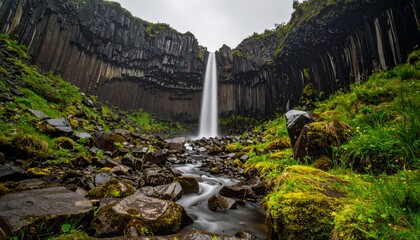 Majestic waterfall cascading down rocky cliffs into lush greenery