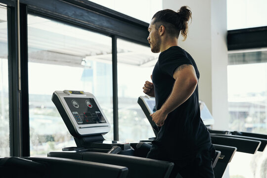Young man running on treadmill in the gym