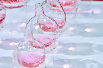 Delicate Glass Vials Containing Shimmering Pink Liquid Capturing Light and Shadow Play
