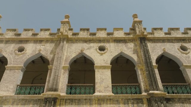 Historic Gothic-style building with pointed arches, crenellated parapets, and ornate finials. Weathered stone and green iron railings evoke colonial charm and architectural elegance.