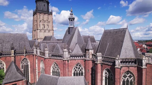 Reveal from closeup to cityscape from above medieval tower town Zutphen, The Netherlands against a blue sky with clouds. Colourful picturesque Dutch city