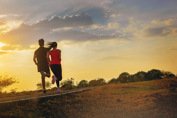 Silhouette of young couple running together on road across the bridge. Couple, fit runners fitness...