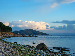 A serene view of a calm sea with a rocky coastline and distant islands under a soft cloudy sky a tranquil and picturesque natural landscape