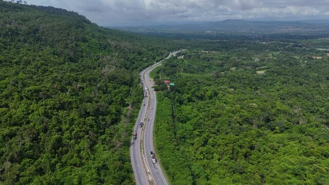 Drone footage of the aerial view of a winding road cutting through lush green forest. Scenic highway number 304 in Thailand links the Bangkok area to Nakhon Ratchasima in the northeastern region