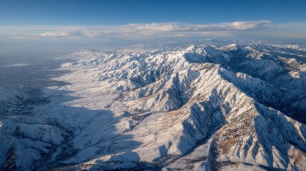 Aerial view of snowy, rugged mountain range under a clear blue sky