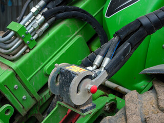 Fototapeta premium A detailed close up photograph of the control joystick and hydraulic connections on a green compact loader used for construction and agricultural work