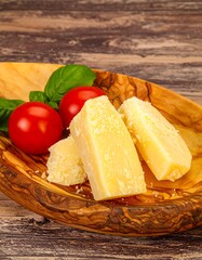 Sliced cheese on wooden bowl with tomatoes and basil