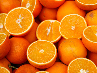 A crate full of fresh and juicy oranges some whole and some cut in half creating a vibrant and refreshing display of citrus fruit at a market
