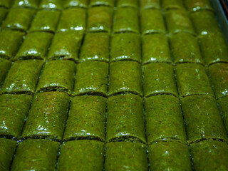 A tray of green pistachio roll baklava also known as fistikli sarma is seen in a full frame shot a rich and sweet traditional Turkish dessert