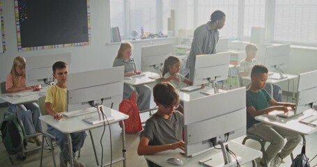 Primary School Students Working on Creative Projects on Computers. African American Teacher Guiding Diverse Kids in Studying Programming During Computer Science Class. Modern STEM Learning. High Angle - Powered by Adobe