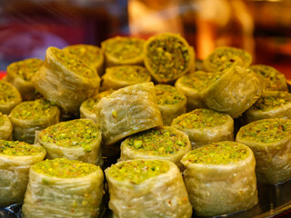 A pyramid stack of delicious baklava pieces generously topped with bright green chopped pistachios a vibrant and tempting dessert display