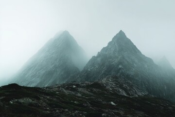 Majestic Mountains Enveloped in Fog Under Mysterious Sky Captured in Serene Natural Landscape