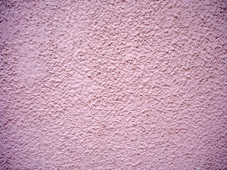 A full frame shot of a light pink stucco wall with a rough and textured surface creating a simple and minimalist abstract background