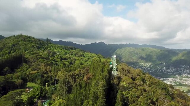 Forest landscape on hill with telecommunication tower on Hawaii island. Aerial view. Revealing shot of Maliki valley in Honolulu, USA. Cloudy summer day.
