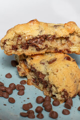 Galleta casera partida a la mitad con chispas de chocolate derretido sobre plato azul, estilo artesanal y tentador ideal para repostería gourmet.