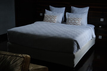 Neatly made bed with white bedding and multiple pillows