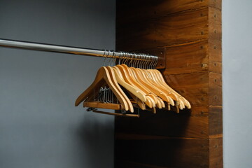 Wooden hangers on chrome rod in open wardrobe