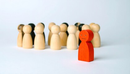 A single red wooden figure amongst a group of light and dark wooden figures