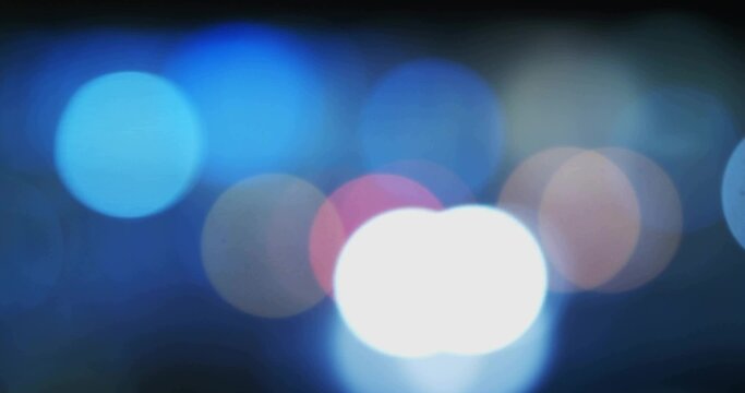 Glowing bright white light blurring in nighttime city street, with blue pink orange bokeh