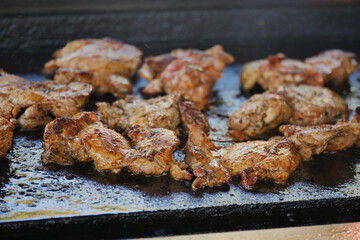 Meat being grilled on hot surface at outdoor event