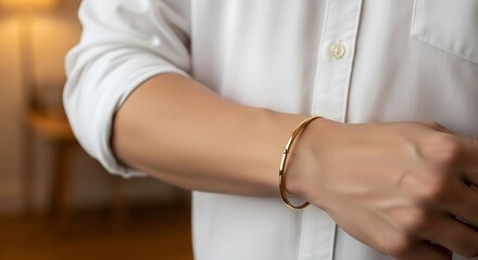 Elegant gold bracelet adorns a person's wrist, showcasing minimalist luxury and refined style