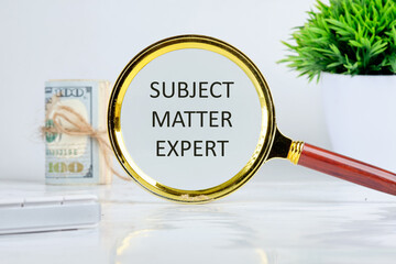 Text Subject Matter Expert written through a magnifying glass on a light background near a roll of money and a pot of green grass