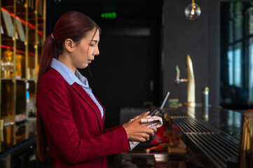 Asian bartender woman cleaning cocktail glass working behind counter bar