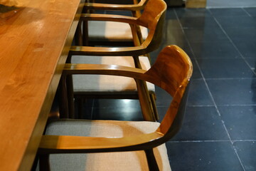 Stylish Wooden Chairs with Cushions at Large Wooden Table in Warm Lamp Light