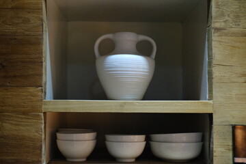 Ceramic Vase with Handles and Stacks of Deep Plates on Shelf