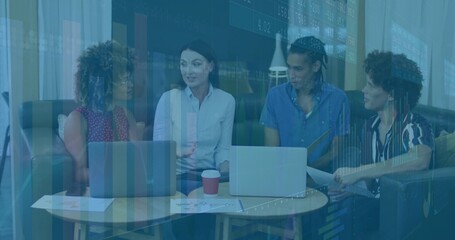 Office colleagues discussing financial charts in office lounge, with open laptops and coffee cup