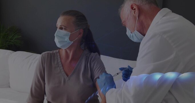 Doctor injecting vaccine into patient arm on couch at home, with syringe and gloves - Powered by Adobe
