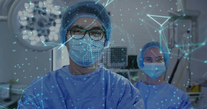 Performing surgery Chinese male surgeon operating in OR, with lights, monitors, holographic display