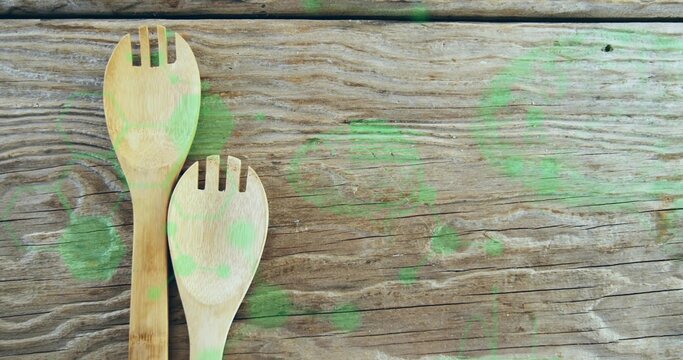 Two bamboo slotted spoons resting left side on kitchen table with green paint stains, copy space