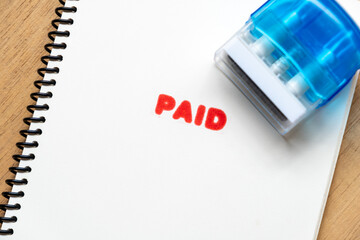 Paid Word Stamped in Red Ink on Spiral Bound Paper