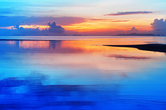Sea beach sunset, calm ocean sunrise, beautiful peaceful tropical island landscape, idyllic seascape, colorful red orange yellow sky, golden sun reflection blue water, tranquil summer holidays, travel