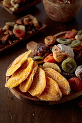 Dried mango slices, tropical fruits, nuts, and raisins on a wooden table.