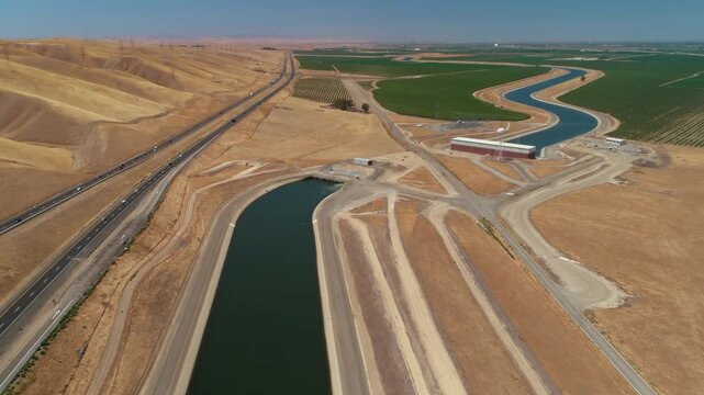 Aerial view of the California Aqueduct, a vital water source, running alongside interstate 5 in California, USA. The aqueduct provides water for agriculture.