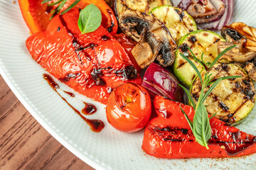 Grilled vegetables with balsamic glaze and fresh herbs on a white plate. top view. copy space