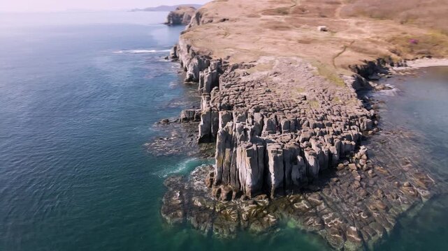 Cape cliffs and basalt columns. Aerial view of Bruce Cape with steep cliffs and iconic basalt columns, surrounded by the clear waters of the Sea of Japan.