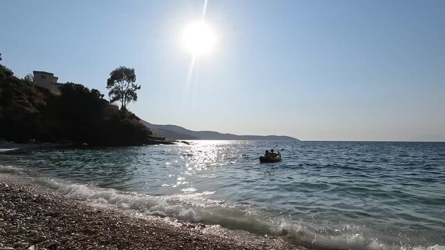 Romantic coastal scene with couple rowing a boat near pebble beach