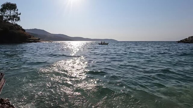 Romantic coastal scene with couple rowing a boat near pebble beach