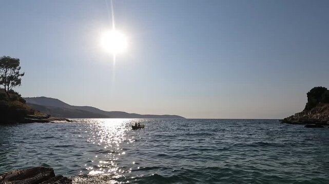 Romantic coastal scene with couple rowing a boat near pebble beach