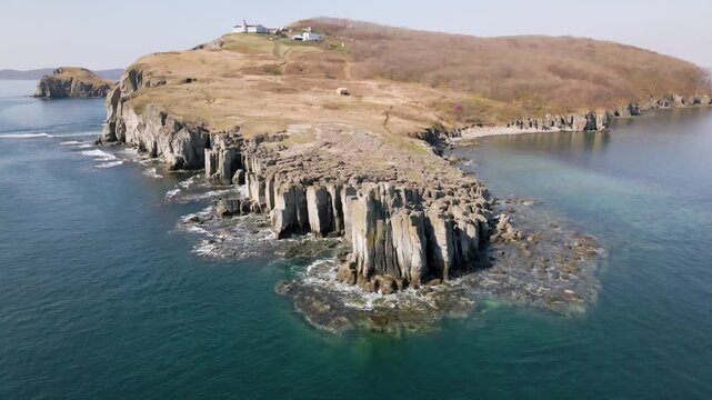Bruce Cape Beacon and Basalt Columns. Drone view of Bruce Cape with the Busse Lighthouse, steep cliffs, and striking basalt columns surrounded by the Sea of Japan. Primorsky Kray, Russia