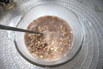 Creamy chocolate oatmeal served in a transparent glass bowl with a spoon, close-up view.