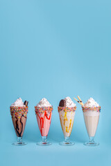 Colorful milkshakes served in glasses on blue background, refreshing sweet drinks perfect for summer, menu design, and food advertising.