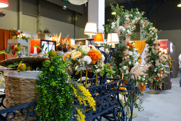 Close-up of an ornate decorative cart with table lamps, flowers, greenery and wicker basket....