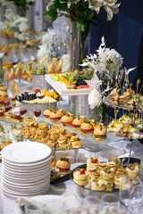 Delicate mini burgers, croissants, and canapes on a banquet table. Stylish appetizer display for weddings, corporate events, or formal gatherings.